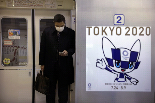 지난달 31일 2020 도쿄 올림픽 홍보 포스터가 붙어있는 지하철에 마스크를 쓴 승객이 탑승해 있다./도쿄=AP연합뉴스
