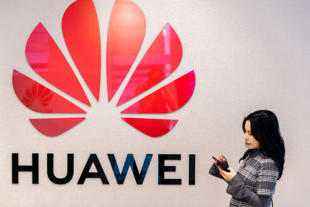 An attendee uses a smartphone as the Huawei Technologies Co. logo sits on a wall at the company‘s Cyber Security Transparency Centre in Brussels, Belgium, on Tuesday, May 21, 2019.  Huawei is prepared to sign European agreements guaranteeing its telecoms technology will not be used for espionage, Huawei Chief EU Representative Abraham Liu said. Photographer: Geert Vanden Wijngaert/Bloomberg