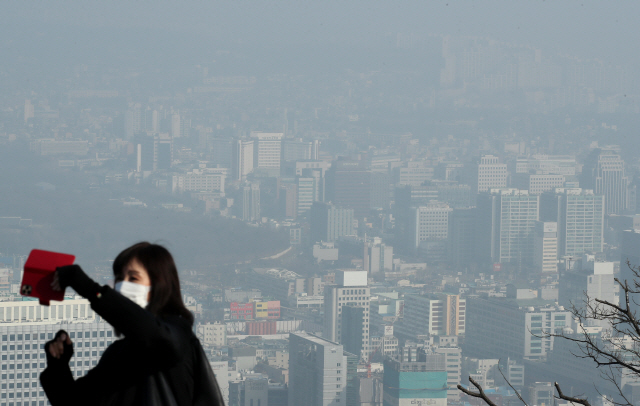 수도권 지역의 미세먼지 농도가 ‘나쁨’ 수준을 보인 14일 서울 남산 N서울타워에서 한 관광객이 휴대폰으로 기념사진을 찍고 있다. 환경부는 15일 오전6시부터 오후9시까지 서울·인천·경기·충남·세종 등 5개 시도에 초미세먼지 위기 경보 ‘관심’ 단계를 발령하고 미세먼지 비상저감조치를 시행한다고 이날 밝혔다. /연합뉴스