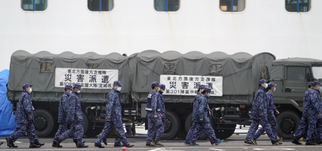 16일 일본 요코하마항에 정박해 있는 크루즈선 ‘다이아몬드 프린세스’호 승객 중 코로나19 양성 반응자 이송을 위해 투입된 일본 자위대원들이 마스크를 쓰고 이동하고 있다.  /요코하마=EPA연합뉴스