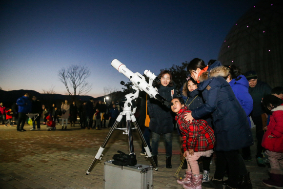 온가족이 함께하는 밤하늘 별자리 여행 캠프가 국립부산과학관에서 열린다. 가족 관람객이 천체를 관측하고 있다./사진제공=국립부산과학관