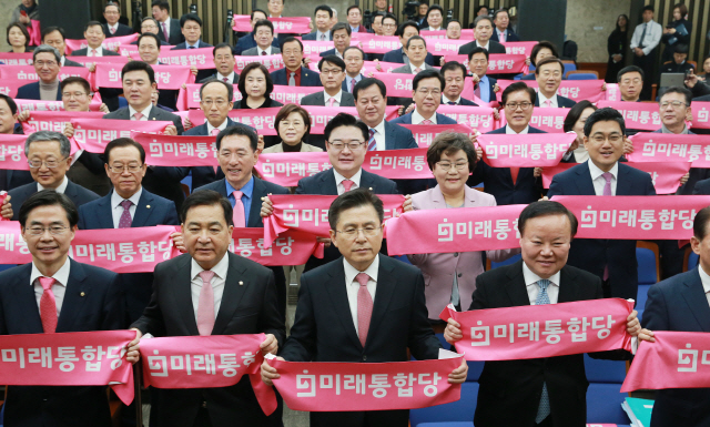 황교안(왼쪽 세번째) 미래통합당 대표와 의원들이 18일 국회에서 열린 첫 의원총회에서 미래통합당 핑크 수건을 펼치며 합당 퍼포먼스를 하고 있다. /연합뉴스