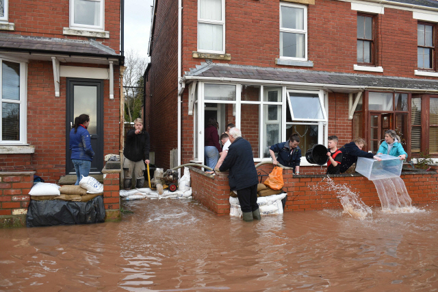 지난주 말 영국을 강타한 폭풍 ‘데니스’로 전역에 물난리가 잇따른 가운데 잉글랜드 남동부 하트퍼드셔주 로스온와이에서 17일(현지시간) 주민들이 집 안으로 범람한 와이강 물을 퍼내고 있다. 데니스의 영향으로 영국에서 지금까지 3명이 숨졌으며 이날 전역에 600건이 넘는 홍수 경보가 내려졌다.  /로스온와이=AFP연합뉴스