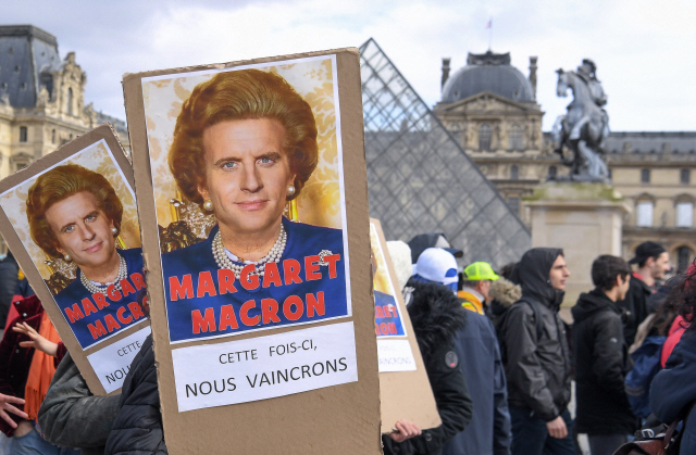 17일(현지시간) 프랑스 파리에서 정부의 퇴직연금 개편안을 반대하는 시위자들이 에마뉘엘 마크롱 대통령을 지난 1980년대 노조의 권한 약화를 꾀했던 마거릿 대처 전 영국 총리에 빗대는 피켓을 들고 있다./파리=AFP연합뉴스