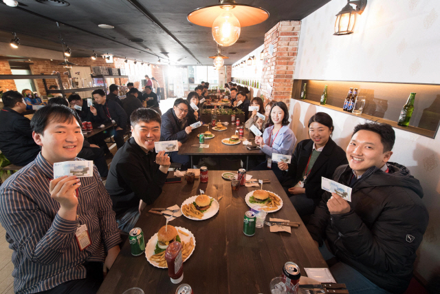 SK하이닉스 직원들이 19일 분당구 정자동 SK하이닉스 사옥 근처에 자리한 ‘킹스버거’에서 식사 도중 성남사랑 상품권을 들고 기념촬영을 하고 있다. SK하이닉스는 지역상권 활성화를 위해 이날부터 매주 수요일마다 ‘지역상권 식당에서 식사하기’ 캠페인을 진행한다는 방침이다. /사진제공=SK하이닉스