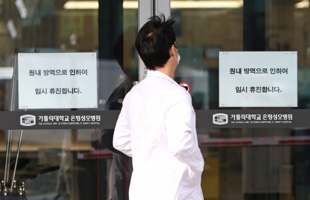 21일 오전 환자 이송요원 1명이 신종 코로나바이러스 감염증(코로나19) 양성 판정을 받은 서울 은평성모병원에 임시 휴진 안내문이 붙어 있다. /연합뉴스