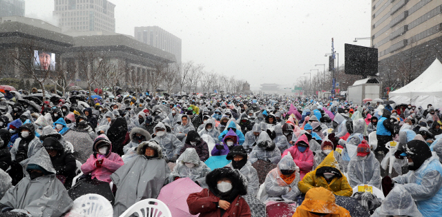 눈이 내린 지난 16일 서울 광화문광장 광장에서 열린 ‘대한민국바로세우기 집회’에 시민들이 참여하고 있다.