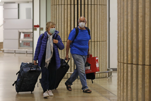 22일(현지시간) 이스라엘 텔아비브의 벤구리온 국제공항에 도착한 입국자들이 마스크를 쓴 채 이동학 있다. /텔아비브=AFP연합뉴스