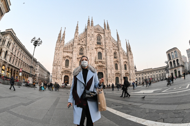 이탈리아에서 코로나19가 확산하는 가운데 24일(현지시간) 한 여성이 마스크를 쓴 채 밀라노 중심가에 있는 두오모성당 앞을 지나가고 있다.    /밀라노=AFP연합뉴스