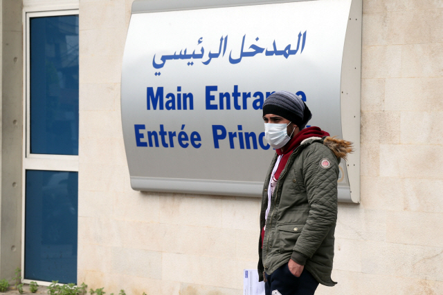 25일(현지시간) 레바논 베이루트의 한 대학병원 앞에서 마스크를 쓴 행인이 서 있다./베이루트=블룸버그