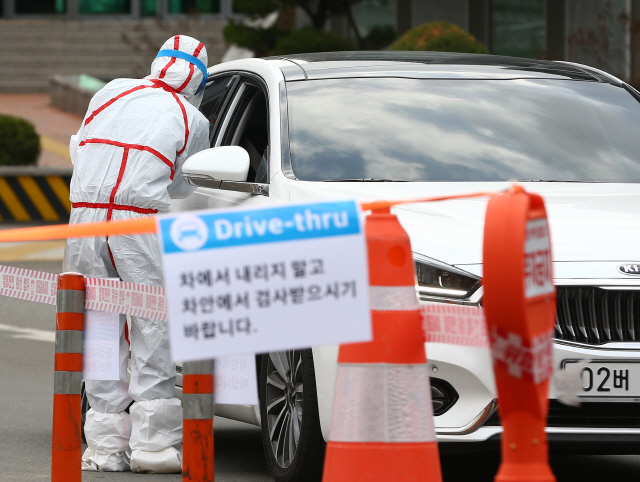 코로나19 검사를 받으러 온 시민들이 27일 대구 남구 영남대병원에 마련된 ‘드라이브 스루’ 선별진료소에서 차에 탄 채 의료진으로부터 진료를 받고 있다.  /연합뉴스