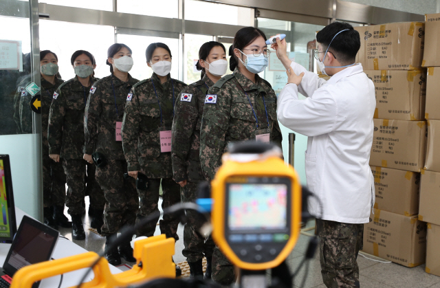 신임 간호장교들이 4일 코로나19 의료지원을 수행하기 위해 경북 경산 국군대구병원으로 들어가기 전 체온 측정을 받고 있다.  /경산=연합뉴스