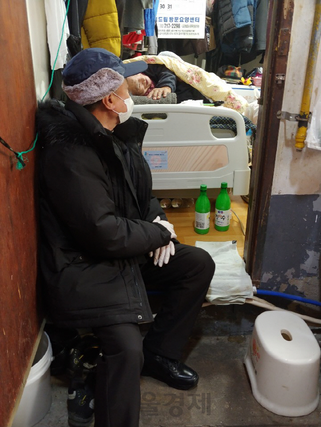 지난 7일 서울 용산구의 한 쪽방촌을 찾은 허근 신부가 거동이 불편해 침상에 누워 있는 주민의 안부를 묻고 있다./최성욱기자
