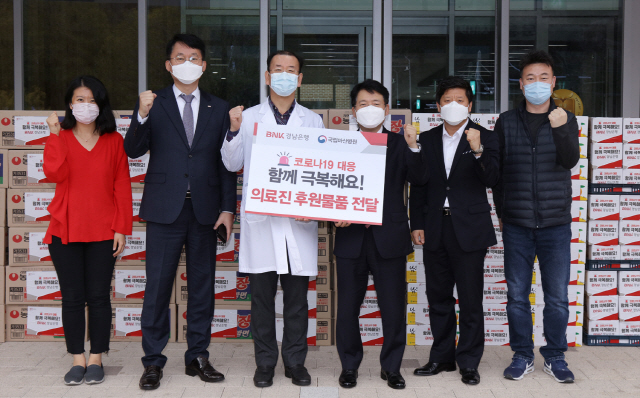 BNK경남은행 안태홍 상무(오른쪽 세번째)가 국립마산병원 박승규 병원장(〃 네번째)에게 ‘코로나19 의료진 후원물품 증서’를 전달하고 있다. /사진제공=BNK경남은행