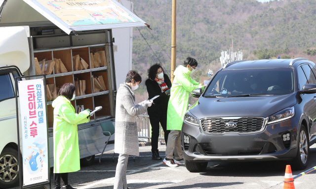 부산 부산진구 시민도서관 주차장에서 직원이 ‘북 드라이브 스루’ 서비스를 신청한 시민에게 책을 전달하고 있다./연합뉴스