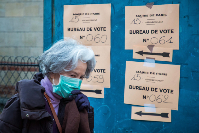 15일(현지시간) 프랑스 파리에서 마스크를 쓴 한 행인이 지방선거 투표소를 알리는 안내문 옆을 지나고 있다./파리=EPA연합뉴스
