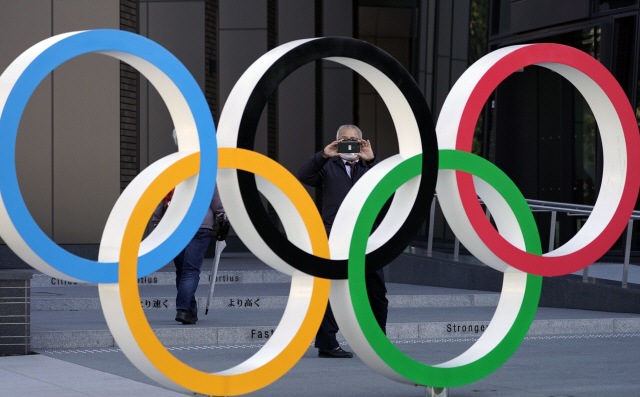 일본 도쿄에 위치한 일본 올림픽위원회 본부 앞에서 16일(현지시간) 한 남성이 오륜기 기념물을 촬영하고 있다. /도쿄=EPA 연합뉴스