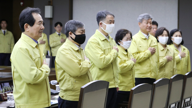 정세균 국무총리(왼쪽)와 국무위원들이 17일 오전 세종시 정부세종청사에서 문재인 대통령이 주재하는 영상 국무회의에 참석해 국기에 경례하고 있다. /세종=연합뉴스