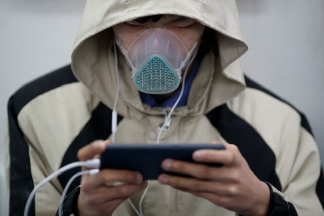 지난 16일 특수 마스크로 무장한 베이징 시민이 지하철에서 스마트폰을 사용하고 있다. 중국 정부의 코로나19 종식 선언 기대에도 불구하고 중국인들의 두려움은 여전하다. /로이터연합뉴스