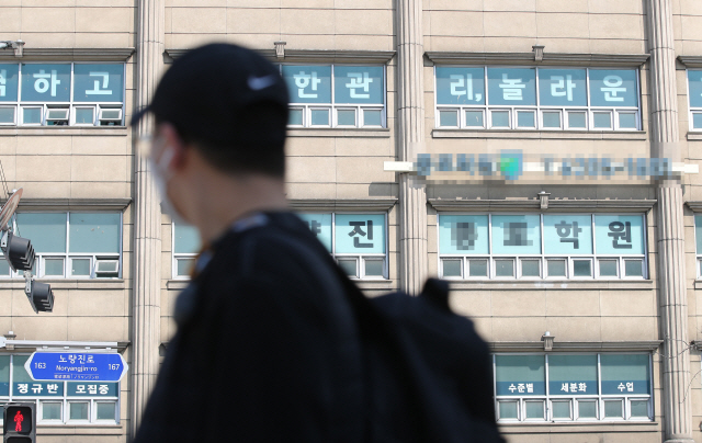 18일 오전 서울 동작구 노량진역 인근 학원 앞에서 마스크를 쓴 시민이 발걸음을 옮기고 있다. /연합뉴스