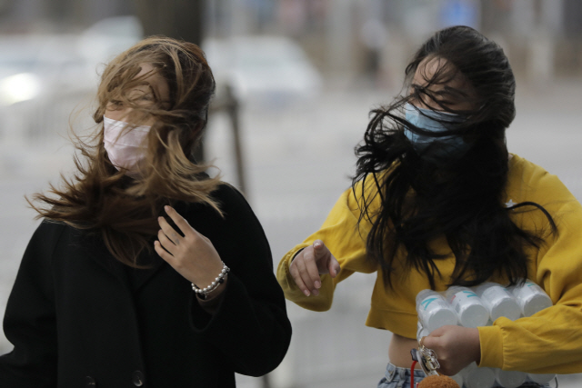 지난 18일 강풍이 불고 있는 가운데 베이징 시민들이 마스크를 한 채 거리를 걷고 있다. /EPA연합뉴스