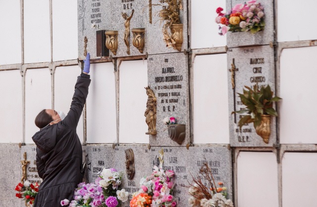 23일(현지시간) 스페인 마드리드의 한 묘지에서 한 여성이 코로나19에 걸려 사망한 한 남성을 위문하고 있다./마드리드=AFP연합뉴스