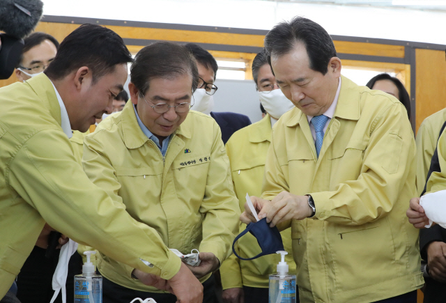 정세균(오른쪽) 국무총리와 박원순(가운데) 서울시장이 25일 서울 용산구 서계동에 위치한 봉제공장을 방문, 공장에서 생산된 면마스크에 필터를 끼우고 있다./연합뉴스