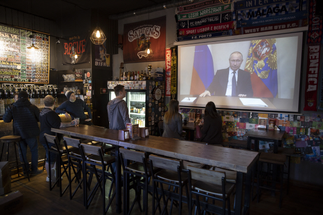25일(현지시간) 러시아 국민들이 모스크바의 한 술집에서 블라디미르 푸틴 러시아 대통령의 연설 방송을 시청하고 있다. 코로나19가 확산되자 이날 푸틴 대통령은 다음달 22일로 예정된 헌법개정안 국민투표를 연기했다./모스크바=AP연합뉴스