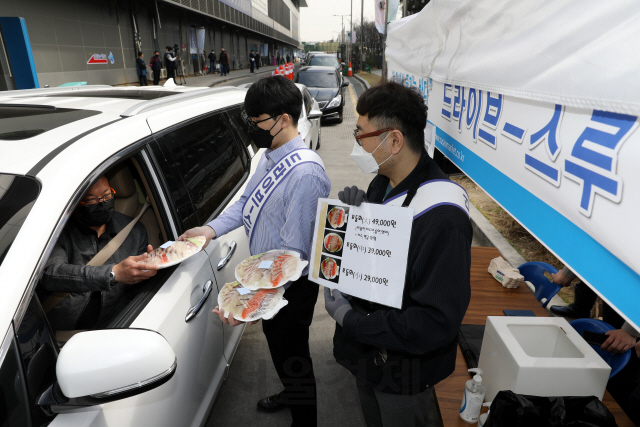 서울 동작구 노량진수산시장에 설치된 드라이브 스루 판매 부스에서 직원이 차 안의 고객에게 모둠회를 건네고 있다. /사진제공=수협