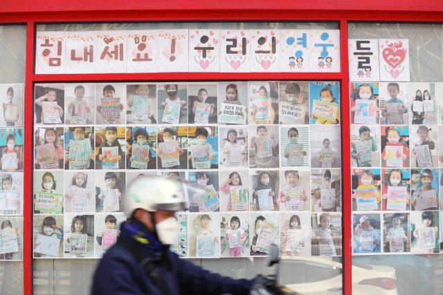 30일 대구 중구 계명대 대구동산병원에서 한 시민이 국민들의 응원 메시지가 붙은 벽을 지나고 있다. 코로나19 사태가 장기화하면서 대구·경북 지역 병원에는 의료진을 응원하는 우편물이 연일 전국에서 답지하고 있다.  /대구=연합뉴스