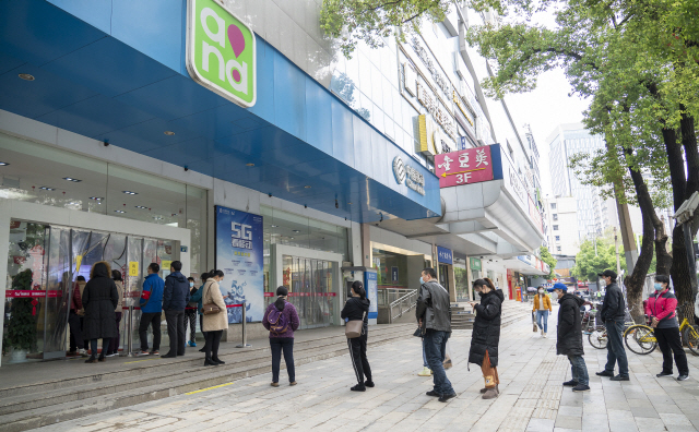 코로나19 발원지인 후베이성 우한에서 휴대폰 매장이 재개장한 가운데 지난 30일 손님들이 입장을 기다리며 길게 줄을 서 있다. /신화연합뉴스