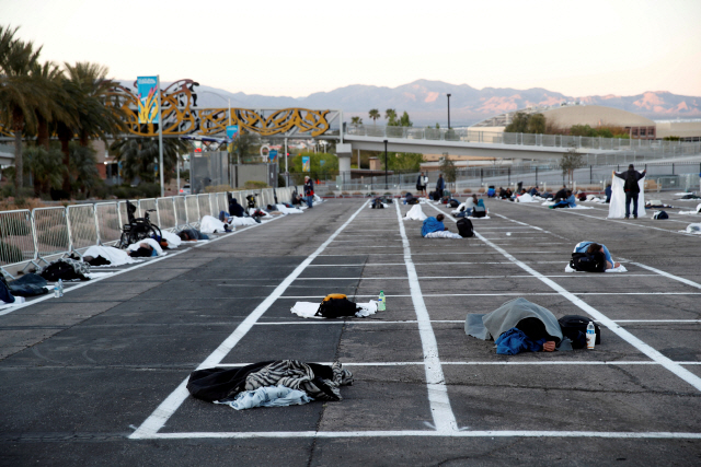 미국 네바다주 라스베이거스의 한 주차장에 표시된 코로나19 확산방지용 ‘사회적 거리두기’ 선 안에 30일(현지시간) 노숙인들이 누워 있다. /라스베이거스=로이터연합뉴스