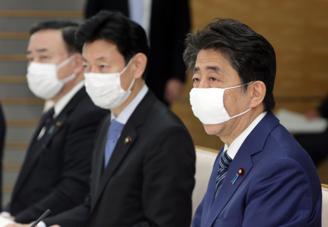 아베 신조(오른쪽) 일본 총리가 지난달 31일(현지시간) 마스크를 쓴 채 도쿄 총리 관저에서 회의를 열고 발언하고 있다. /도쿄=EPA연합뉴스