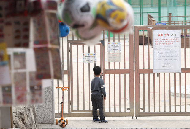 지난달 31일 서울 용산구 한 초등학교에서 한 어린이가 닫힌 문 너머 운동장을 바라보고 있다. /연합뉴스