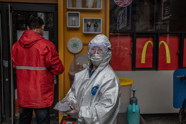 지난 2일 중국 후베이성 우한에서 전신 방호복을 입은 맥도널드 직원이 입구에 서있다. /EPA연합뉴스