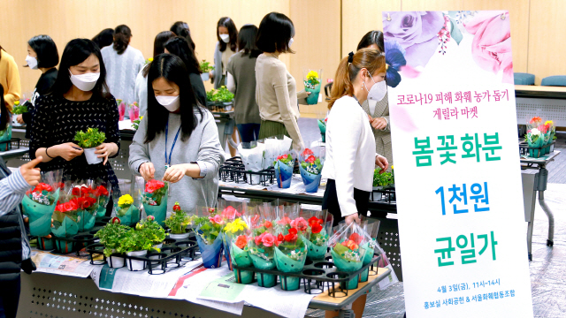 3일 서울 광화문 우리카드 본사에서 열린 ‘화훼농가 돕기 게릴라 마켓‘ 행사에서 우리카드 임직원들이 꽃 화분을 구매하고 있다./사진제공=우리카드