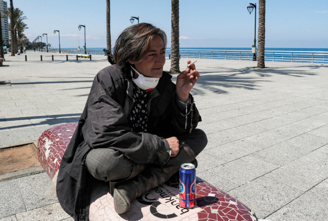 한 여성이 레바논 베이루트 해안가에서 N95 마스크를 내리고 담배를 피고 있다. 미국 질병통제예방센터(CDC)는 흡연자도 코로나19 고위험군으로 분류해 관리하고 있다. /베이루트=AFP연합뉴스