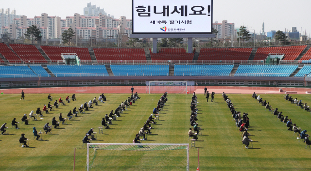 지난 4일 오전 경기도 안산시 와스타디움에서 안산도시공사 직원 공개채용 필기시험이 치러지고 있다. 안산도시공사는 코로나19 감염 차단을 위해 축구장 한가운데 좌우 5m 간격으로 140여개의 책상과 의자를 놓고 야외시험을 진행했다.  /안산=연합뉴스