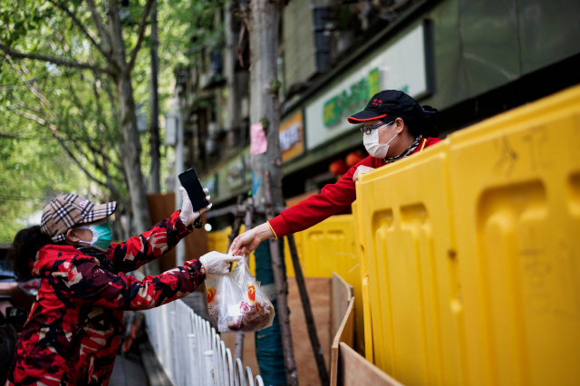 6일 중국 후베이성 우한에서 한 배달원이 손님에게 음식을 건네고 있다./우한=AFP연합뉴스