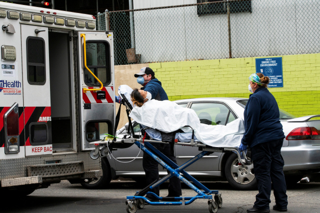 미국 뉴욕 퀸스 지역에 있는 엘름허스트 병원 앞에서 5일(현지시간) 구급요원들이 신종 코로나바이러스 감염증(코로나19) 환자를 구급차로 옮기고 있다. /뉴욕=로이터연합뉴스