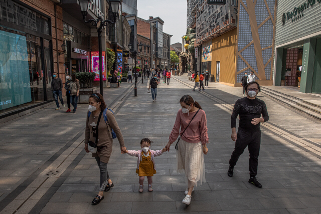 ‘도시 봉쇄’ 해제를 이틀 앞둔 지난 6일 중국 후베이성 우한 시내에서 한 가족이 마스크를 한채 쇼핑가를 걷고 있다. /EPA연합뉴스