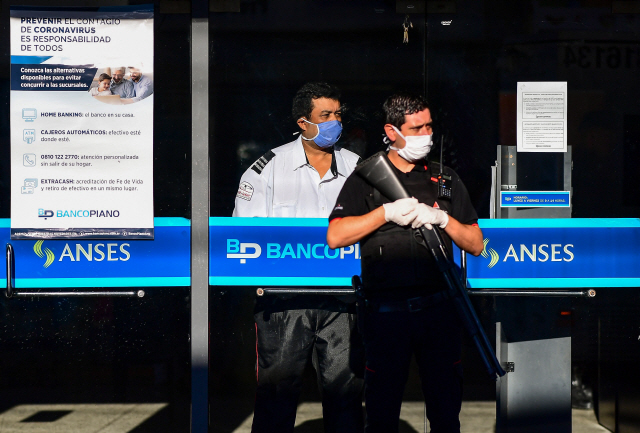 지난 4일(현지시간) 아르헨티나 수도 부에노스아이레스에서 마스크를 쓴 보안직원이 총을 든 채로 은행 앞을 지키고 있다./부에노스아이레스=AFP연합뉴스