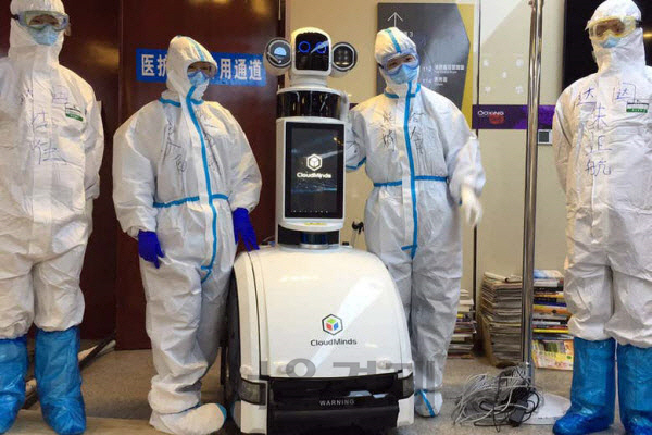 중국 우한의 우창병원에서 의료진이 환자에게 음식과 약을 제공하고 청소도 하는 로봇과 포즈를 취하고 있다./사진=클라우드마인드