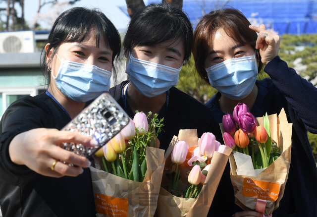 8일 오후 코로나19 전담병원인 서울 중랑구 서울의료원에서 고된 근무를 마치고 퇴근하는 의료진들이 건네받은 튤립 꽃다발을 들고 밝게 미소 짓고 있다. 주한 네덜란드 대사관은 코로나19 최전선에 있는 서울의료원 의료진에게 응원과 감사의 마음을 담은 튤립 7,000송이를 전달했다./오승현기자 2020.04.08