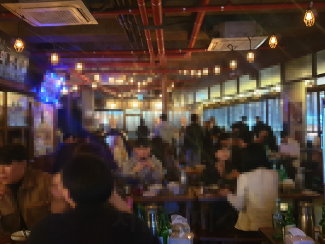 지난 10일 밤 서울 마포구 홍대입구 인근 한 술집. 마스크를 착용하지 않고 들어갔지만 직원은 아무 제지도 하지 않았고 사회적 거리두기 시행에도 같은 다른 손님들과 인접한 테이블에 안내했다./허진 기자