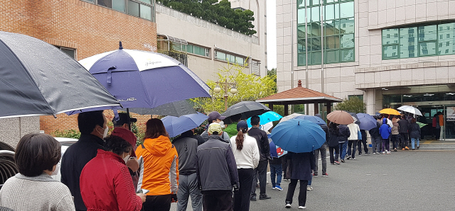 11일 오후 울산시 남구 옥동 울산보훈지청 사전투표소에서 줄을 길게 늘어선 유권자들이 갑작스럽게 비가 내리자 우산을 꺼내 쓰거나 그대로 비를 맞으면서 투표 순서를 기다리고 있다./연합뉴스