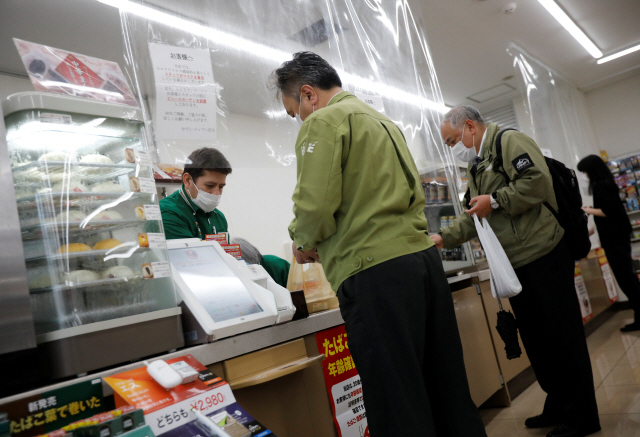 일본 도쿄의 편의점 세븐일레븐 계산대에 13일 신종 코로나바이러스 감염증(코로나19) 전염을 막기 위해 직원과 고객 사이를 차단하는 비닐 커튼이 쳐져 있다./도쿄=로이터연합뉴스