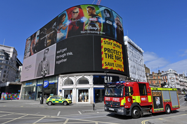 13일 영국 런던 피카딜리 서커스 광장의 대형 전광판에 코로나19 확산 예방과 의료 붕괴를 막기 위해 집에 머물러 달라는 영국 정부의 메시지가 띄워져있다./AFP연합뉴스
