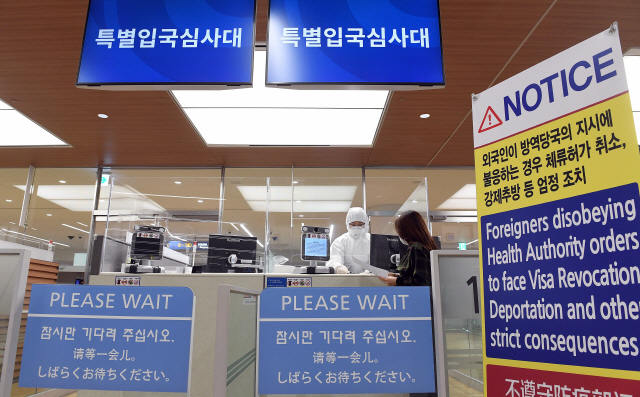 인천국제공항 출입국 외국인청 입국심사관이 전신 방호복을 입은 채 유증상자 전용 입국심사대에서 입국심사 후 자가격리 지침을 설명하고 있다. /영종도=연합뉴스