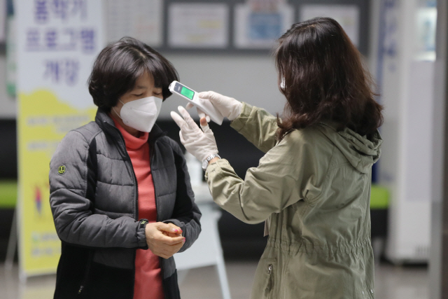 제21대 총선 투표일인 15일 오전 광주 남구 봉선동 남구종합문화예술회관에 마련된 투표소에서 한 선거인이 투표장으로 입장하기 전 발열 체크를 하고 있다./광주=연합뉴스